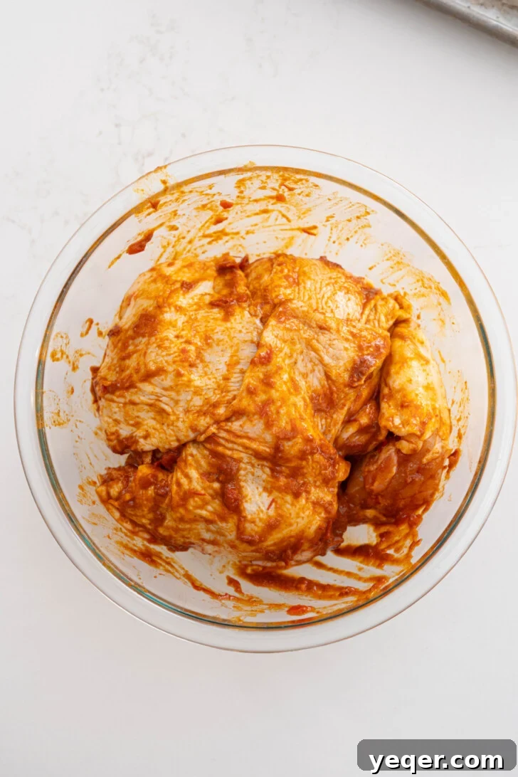 Spicy Sweet Harissa Honey Chicken 5 Marinated chicken thighs in a bowl.