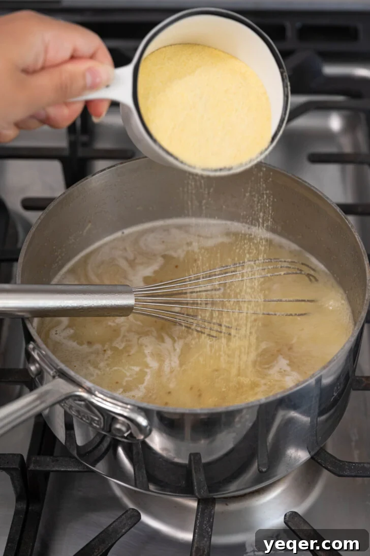 Baba's Moroccan Semolina Cold Remedy 5 Fine semolina flour being slowly and evenly dusted into the boiling water mixture, accompanied by continuous, vigorous whisking to prevent any lumps from forming.
