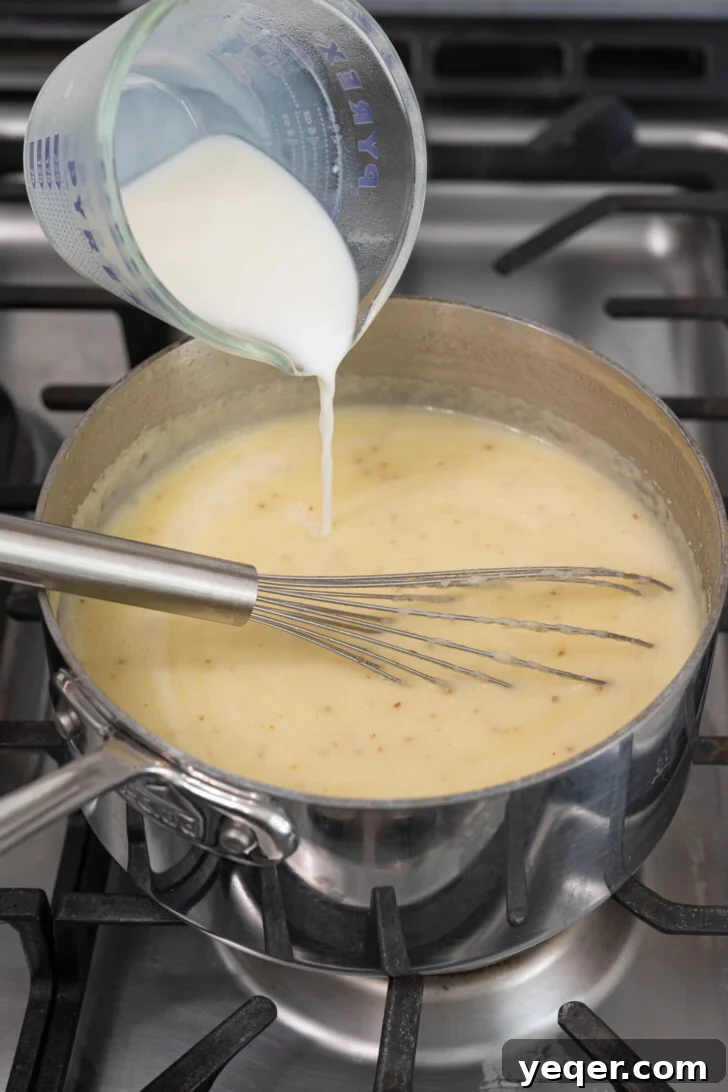 Baba's Moroccan Semolina Cold Remedy 6 Creamy milk being steadily poured into the thickening semolina soup, with continued whisking to ensure smooth incorporation and a luxurious texture.