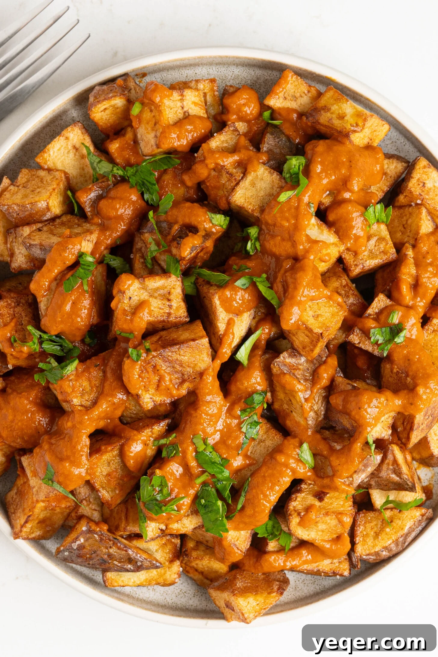 Fiery Spanish Patatas Bravas 2 A plate of patatas bravas, garnished with fresh parsley.
