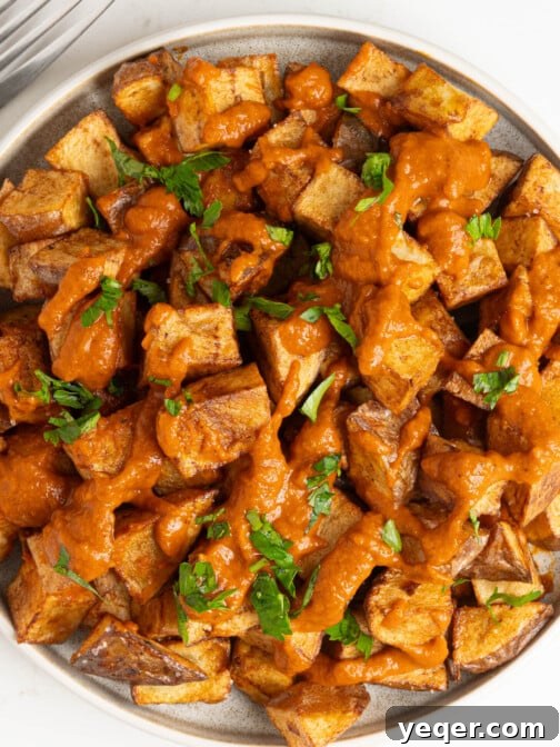 A plate of patatas bravas, garnished with fresh parsley.