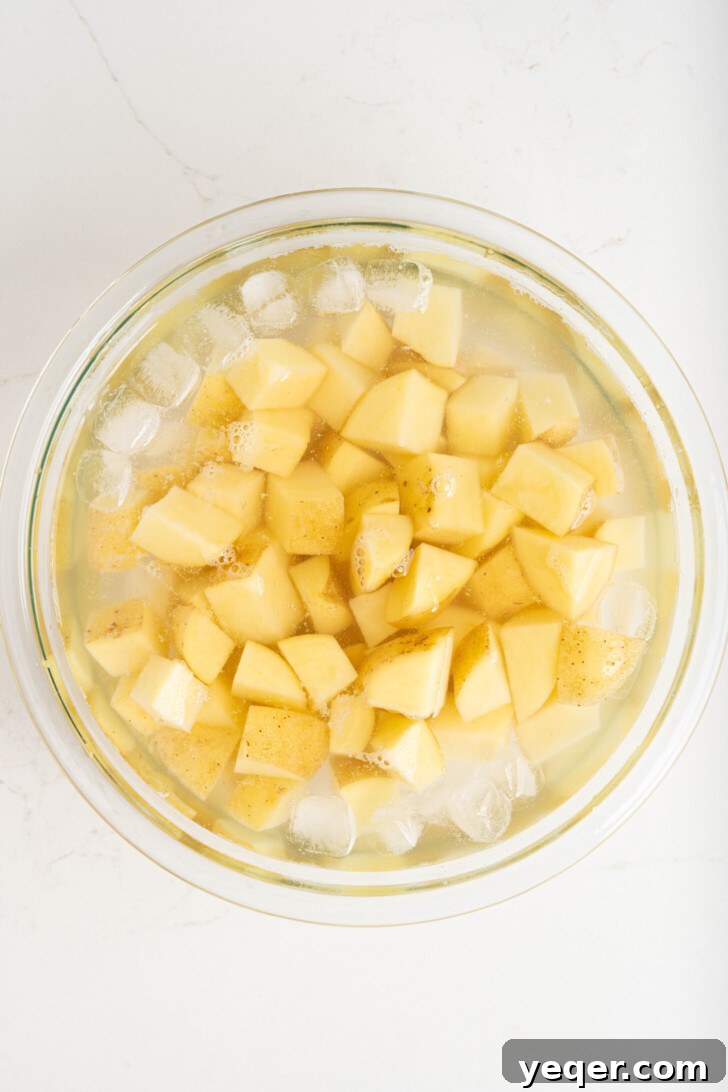 Fiery Spanish Patatas Bravas 4 Cubed potatoes soaking in a bowl of ice water, preparing for frying.