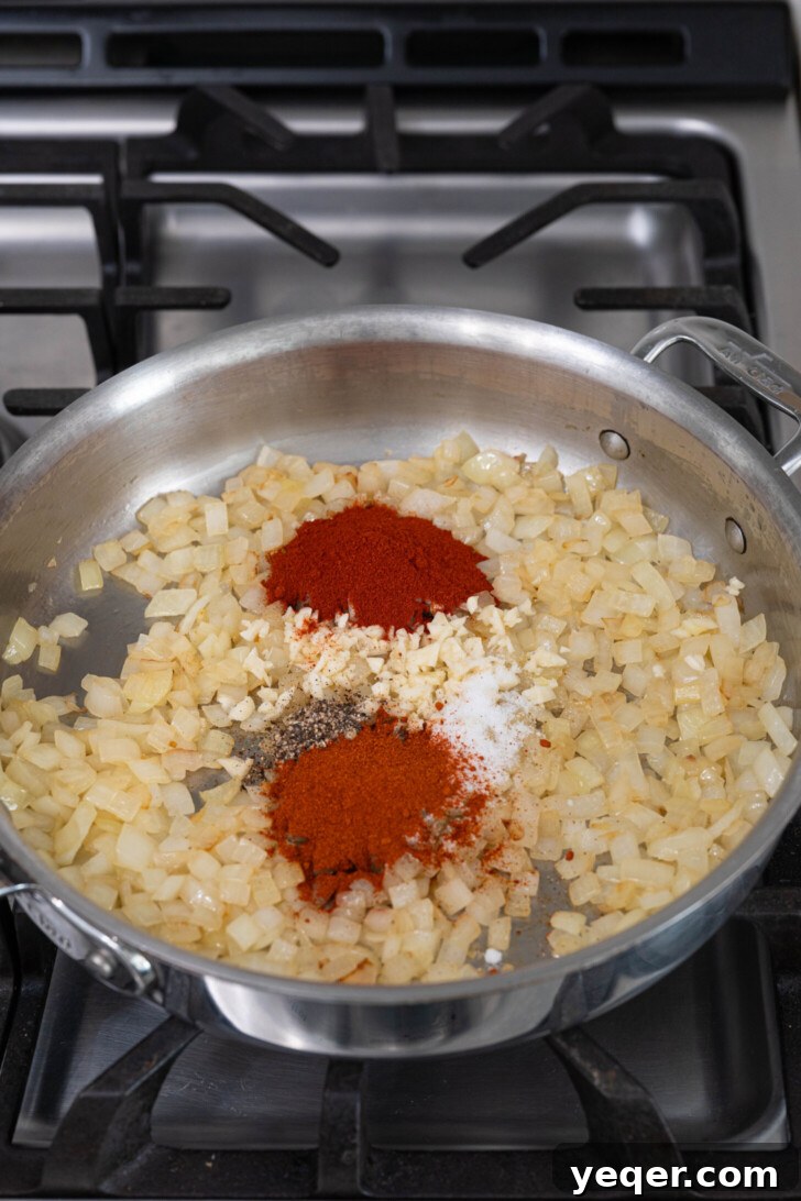 Fiery Spanish Patatas Bravas 5 Onions, minced garlic, and paprika being sautéed in a pan to build the salsa brava base.