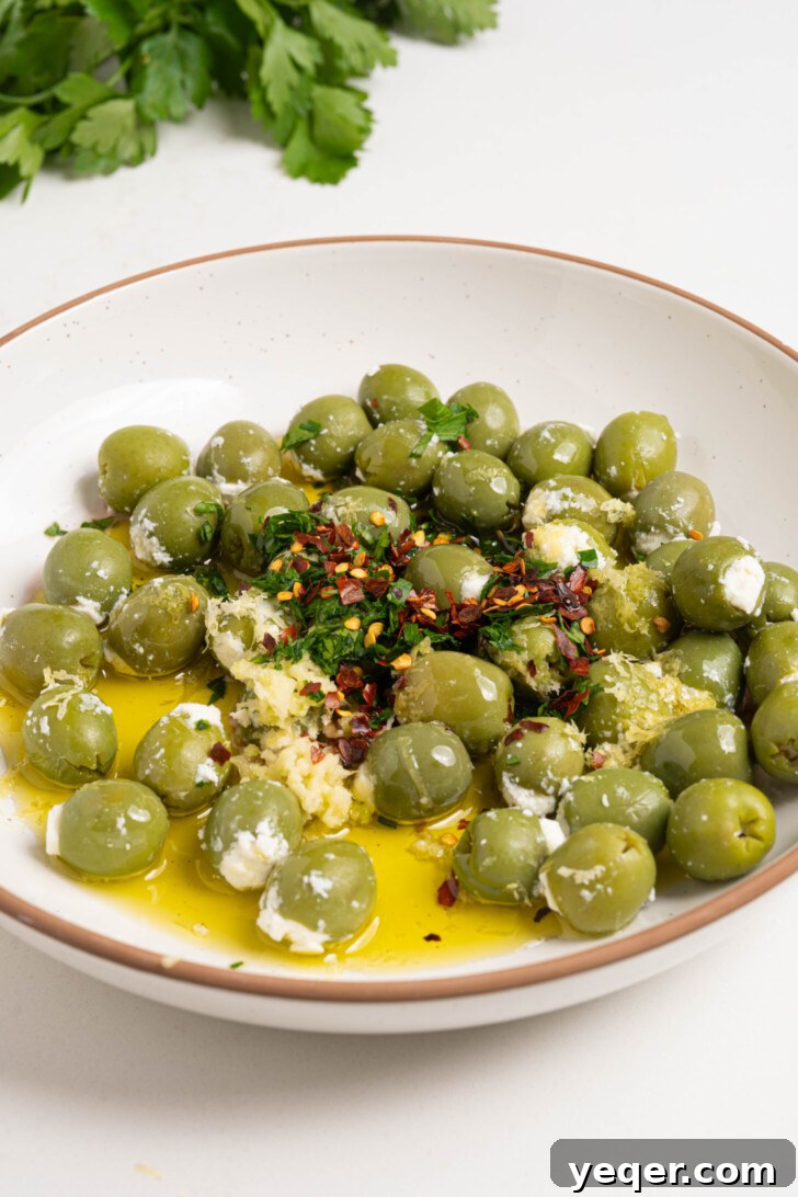 Exquisite Marinated Olives 5 A vibrant close-up of a bowl filled with stuffed olives being gently tossed with a rich, aromatic marinade of oil, fresh herbs, and various spices.
