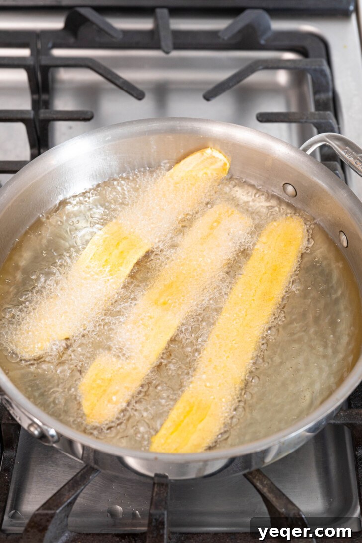 Crispy Plantain Delights 7 Thin plantain strips frying in hot oil in a pan.