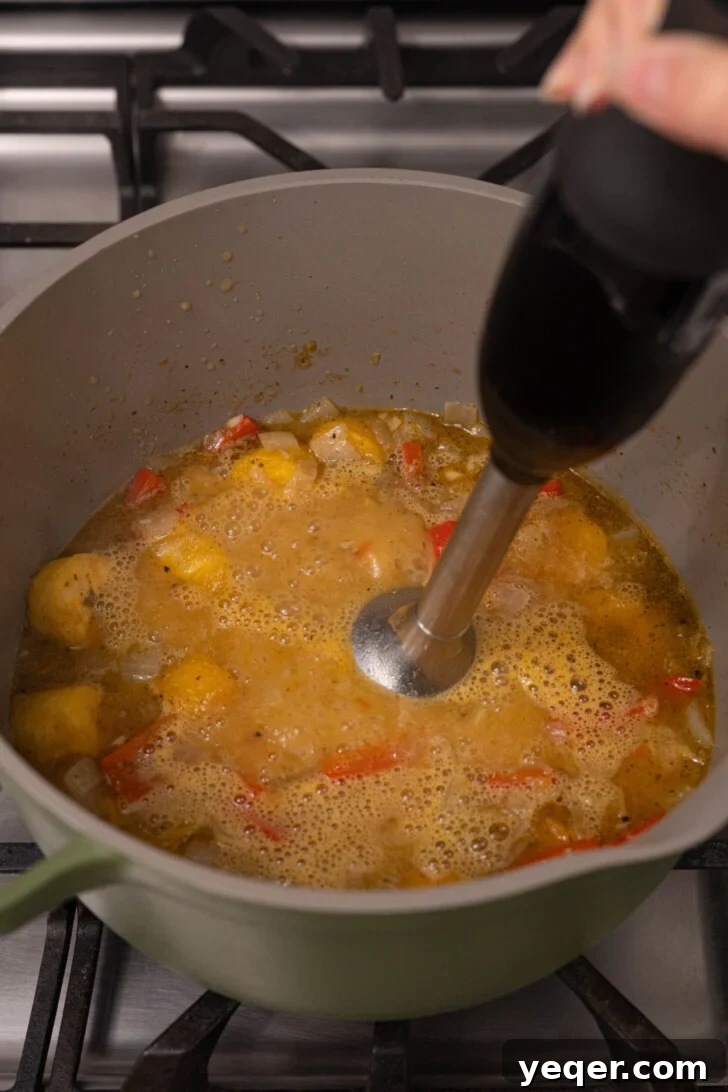 Plantain soup blending with an immersion blender.
