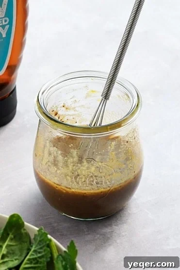 Signature Balsamic Vinaigrette 2 A jar of balsamic dressing with salad in the corner.
