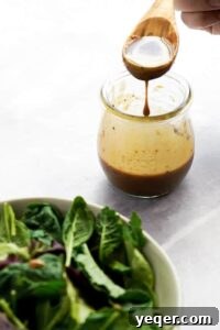 Signature Balsamic Vinaigrette 5 A jar of balsamic dressing with salad in the corner.