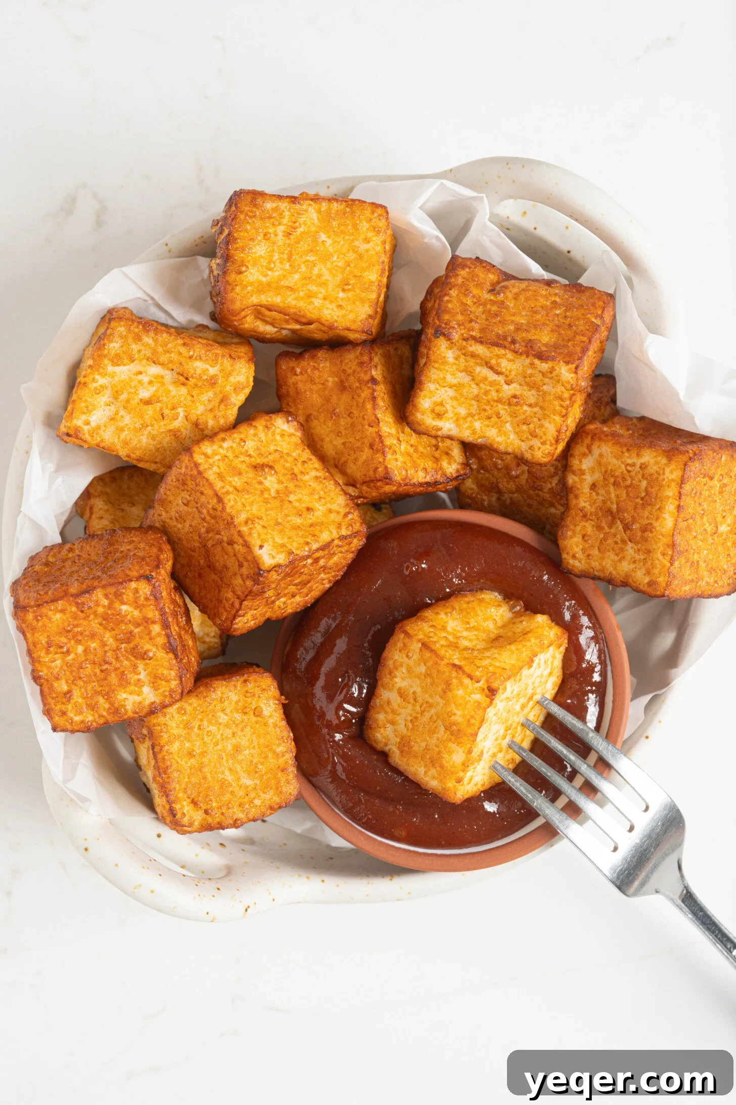 Crispy Queso Frito with Tropical Guava Drizzle 2 A bowl of golden brown queso frito with a side of vibrant guava sauce, garnished with fresh herbs.