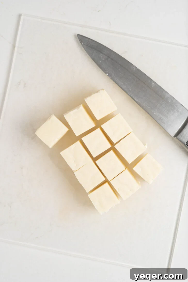 Crispy Queso Frito with Tropical Guava Drizzle 6 A block of queso de freir cheese, meticulously cubed into uniform pieces on a cutting board.