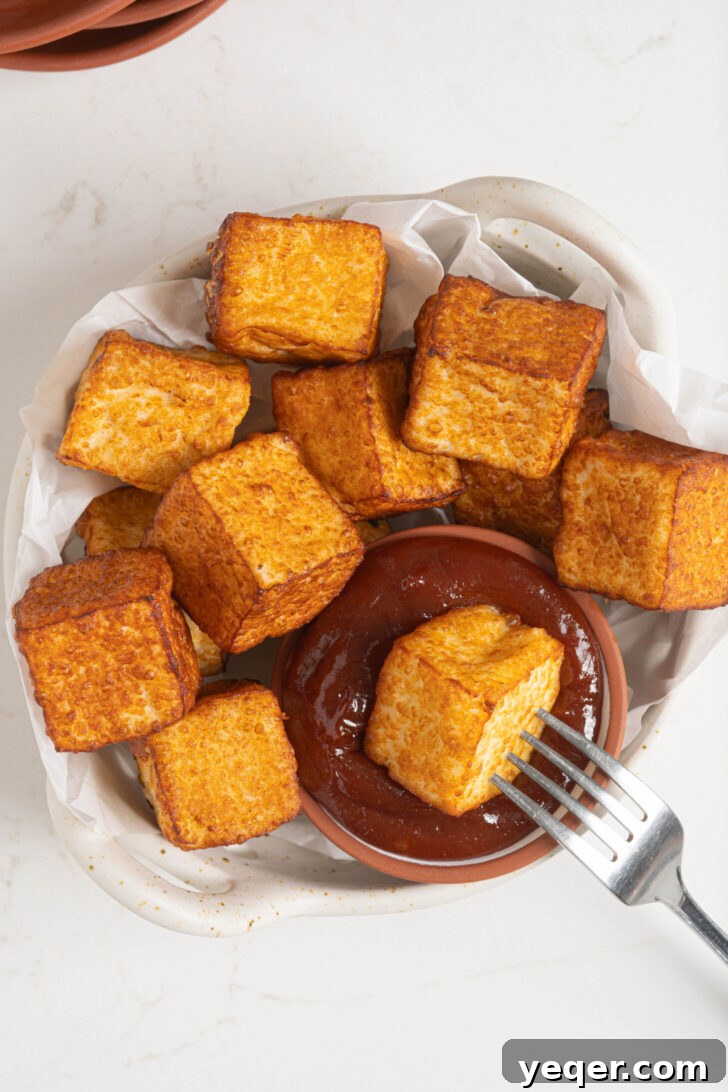 Crispy Queso Frito with Tropical Guava Drizzle 8 A serving bowl filled with freshly fried queso frito, artfully arranged next to a small dish of guava sauce.