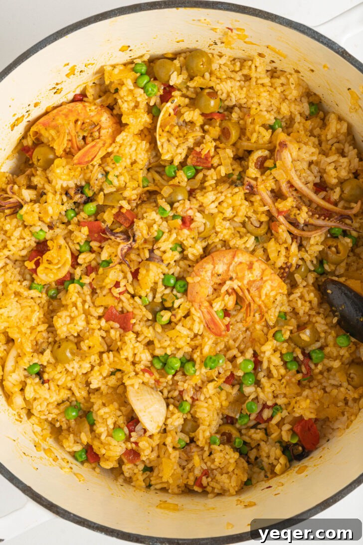 Vibrant Puerto Rican Seafood Rice 9 Cooked Puerto Rican seafood rice with frozen peas being fluffed in.