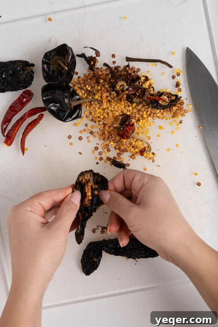Homemade Harissa Spice Mix 5 Hands meticulously removing seeds from dried peppers, a crucial step for controlling heat.
