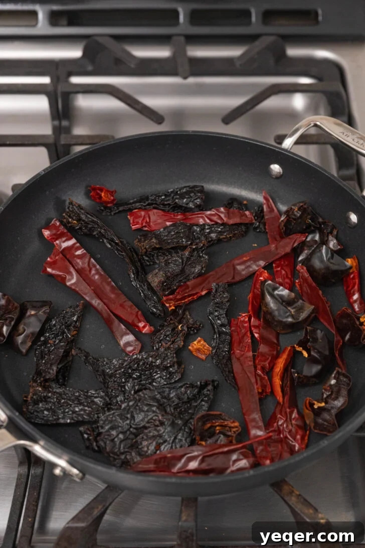 Homemade Harissa Spice Mix 6 Dried peppers gently toasting in a frying pan, releasing their smoky aromas.