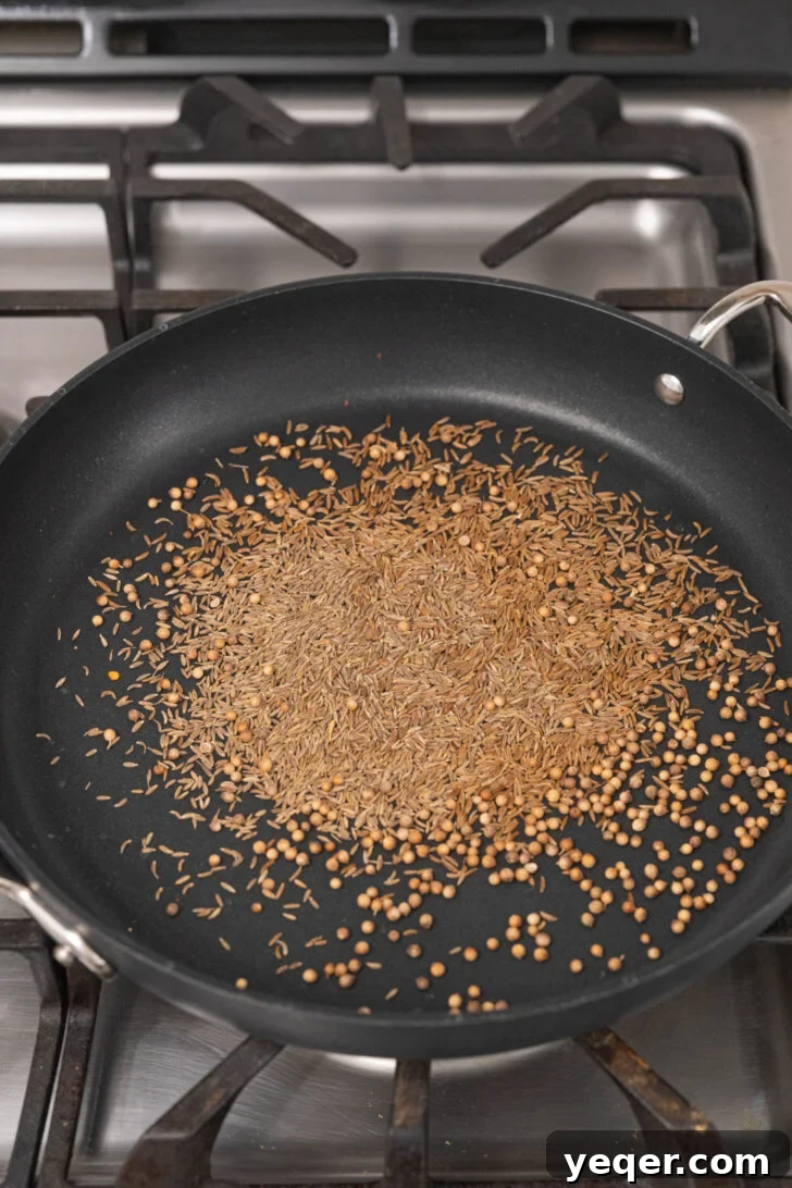 Homemade Harissa Spice Mix 7 Whole spices, including cumin, caraway, and coriander, toasting in a pan until fragrant.