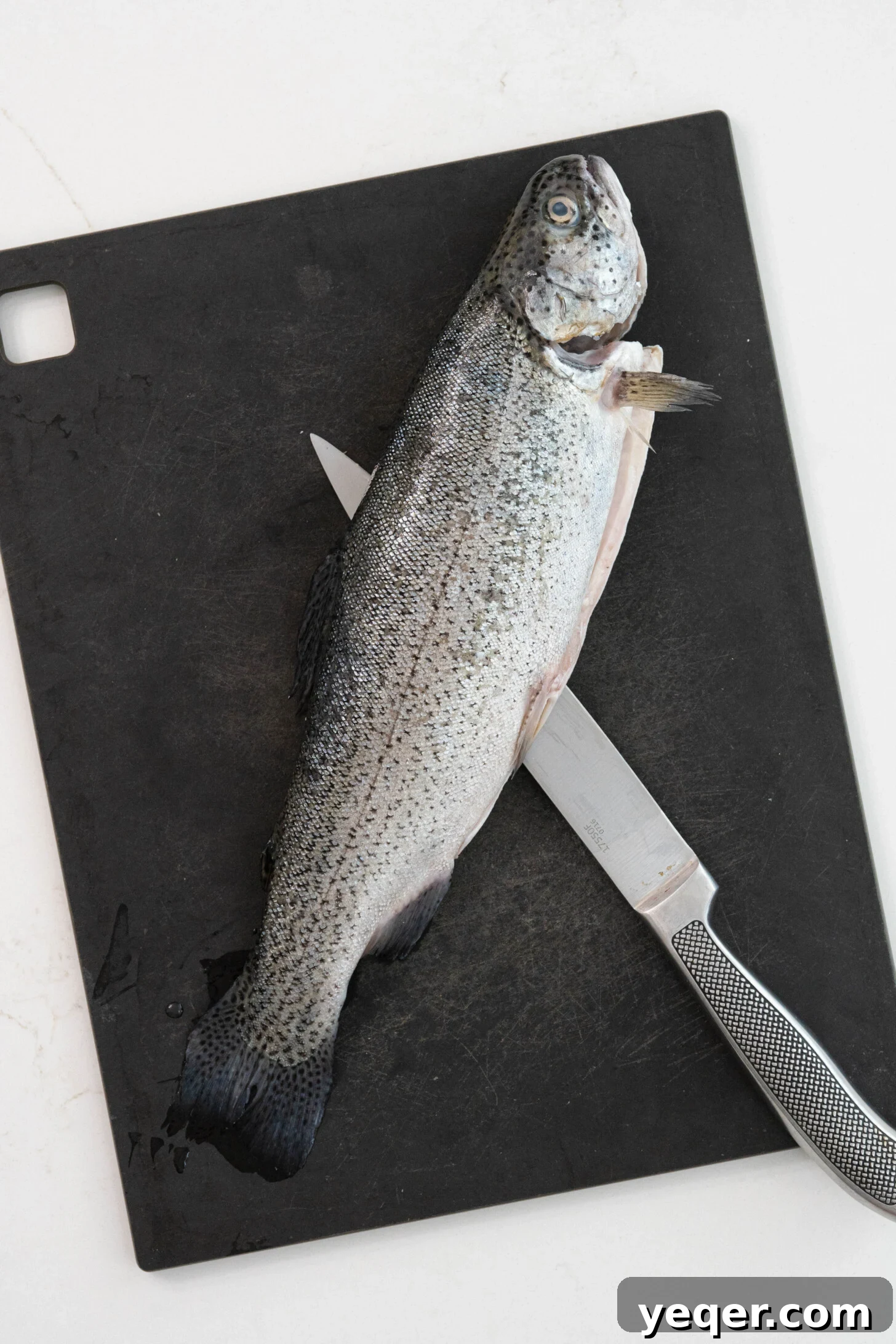 Crispy Whole Fried Mojarra 11 A whole, fresh fish lying on a rustic wooden cutting board, prepped and ready for the Mojarra Frita recipe.
