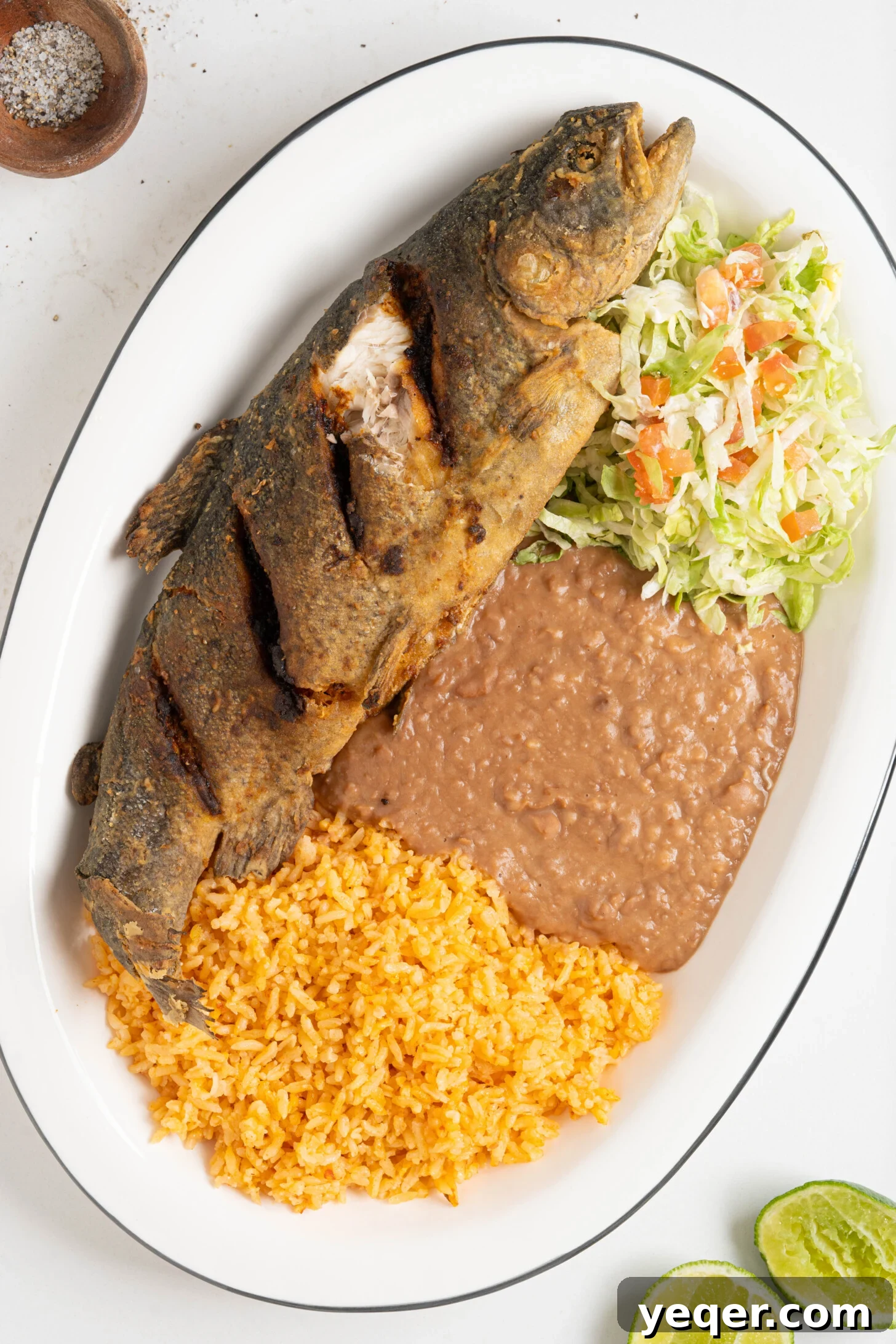 Crispy Whole Fried Mojarra 8 A beautifully presented platter of Mojarra Frita, accompanied by fluffy rice, savory beans, and a refreshing salad, ready to be enjoyed.