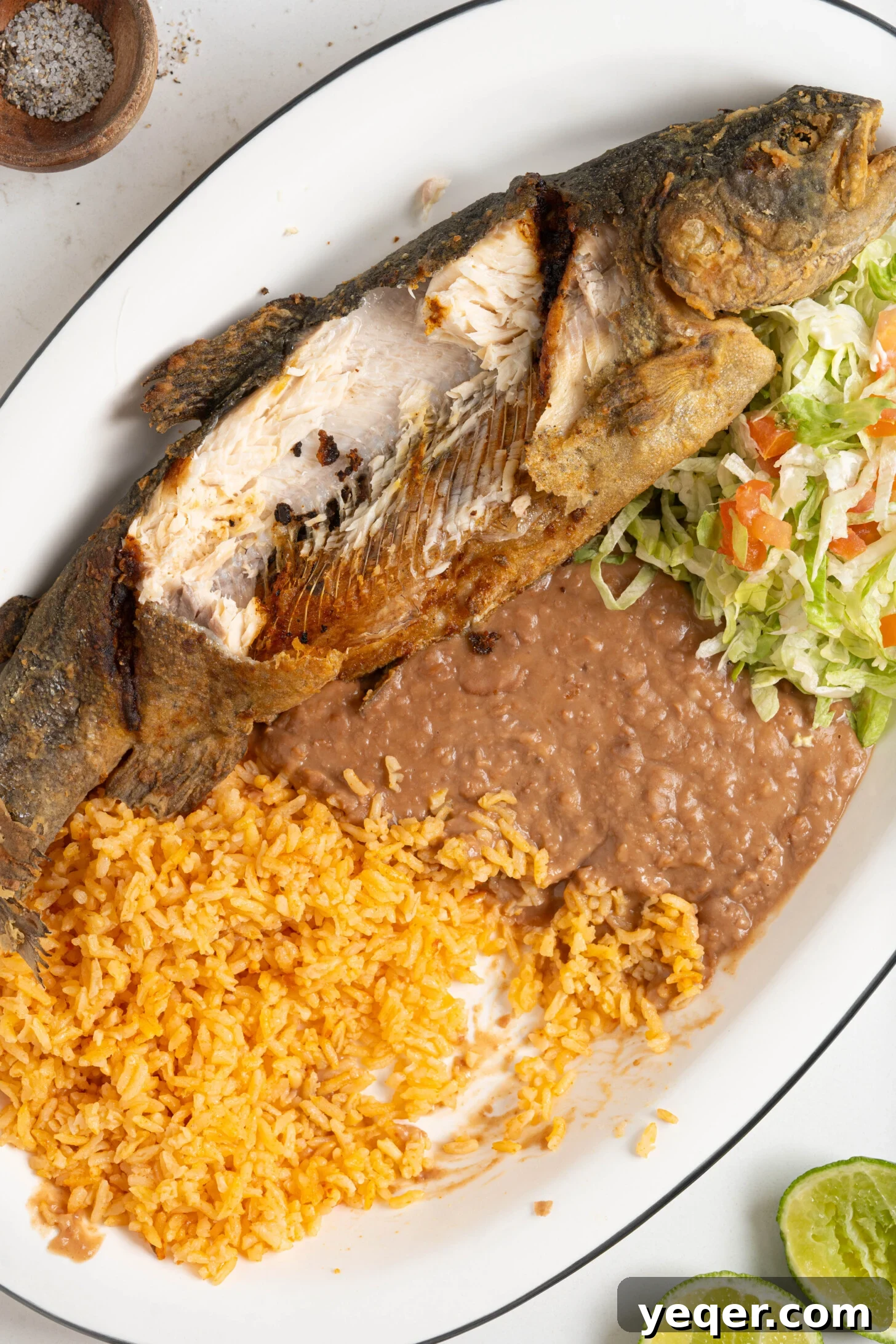 Crispy Whole Fried Mojarra 9 A close-up view of a perfectly fried Mojarra Frita, garnished with fresh herbs, alongside rice, beans, and salad, highlighting its crispy texture.