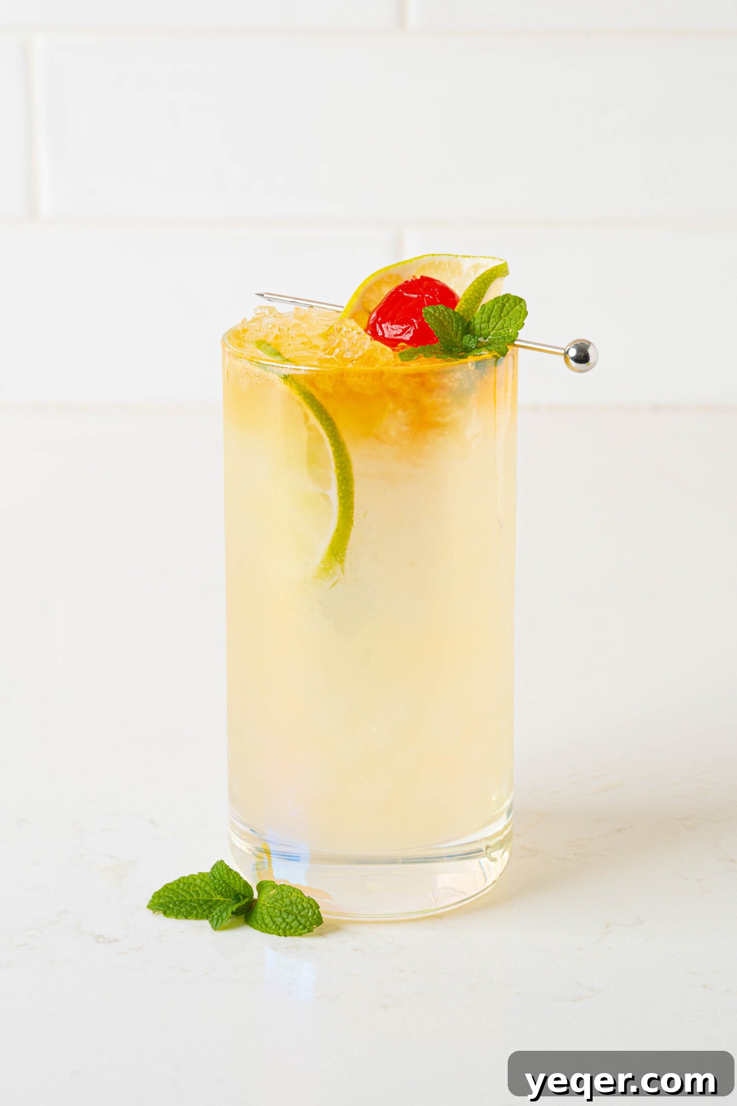 Authentic Mai Tai Cocktail 7 A vibrant Mai Tai cocktail, expertly garnished with mint and a lime wedge, resting on a clean white surface, showcasing its appeal.