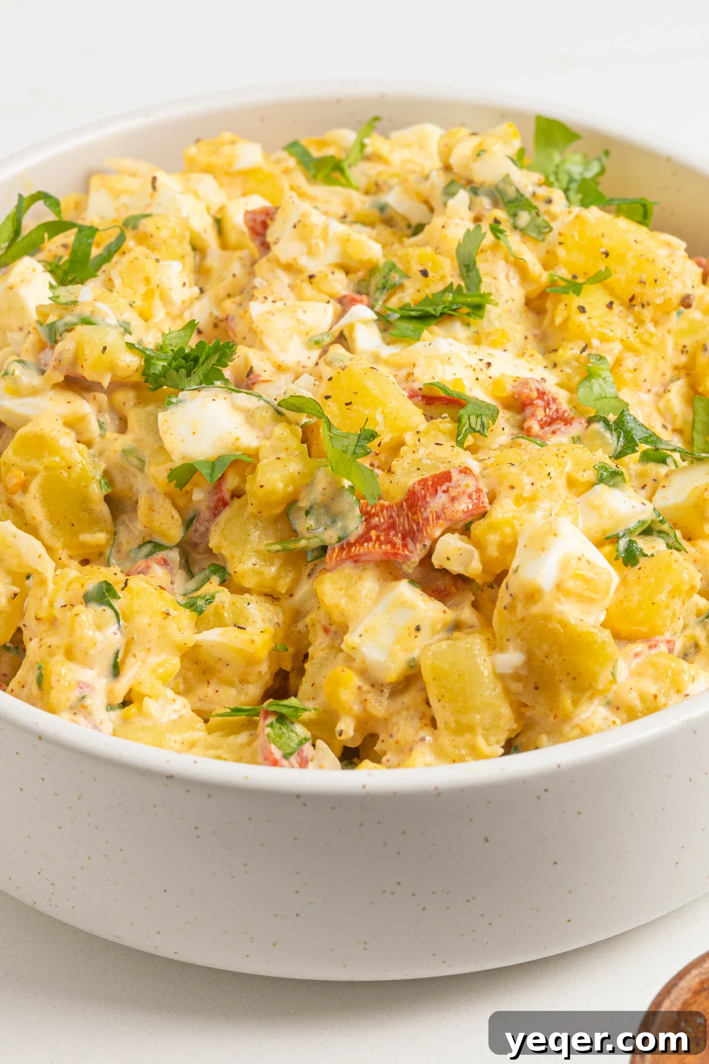 Puerto Rican Potato Salad 2 A bowl of ensalada de papa, garnished with fresh herbs.