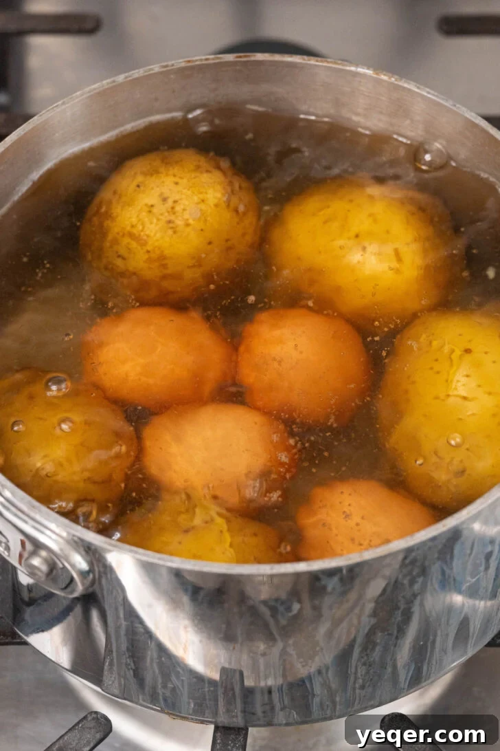 Puerto Rican Potato Salad 5 A pot of boiling eggs and potatoes on a stovetop.