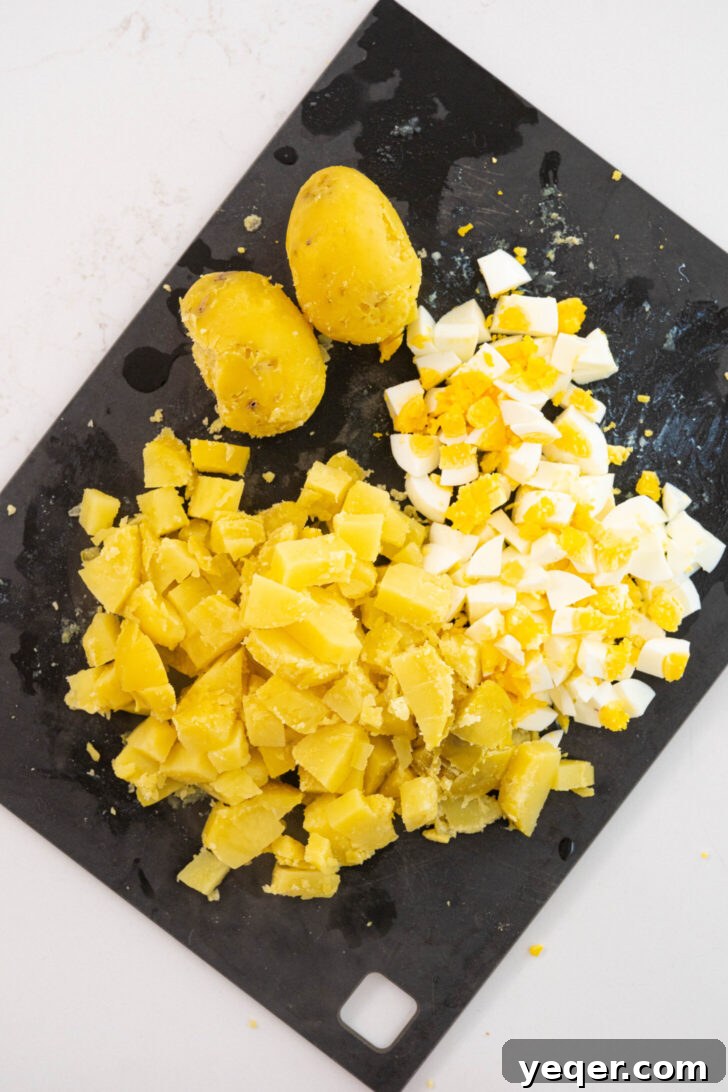 Puerto Rican Potato Salad 7 Chopped potatoes and hard-boiled eggs neatly arranged on a cutting board, ready for mixing.