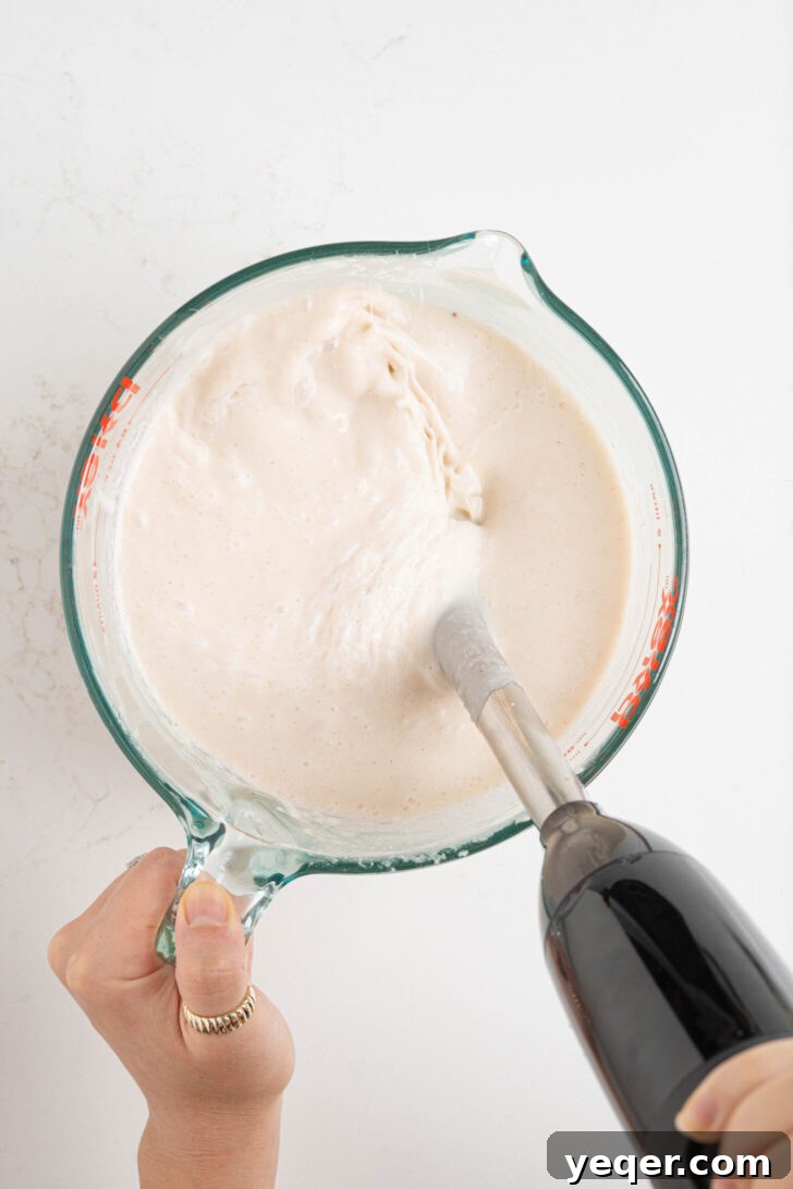 Puerto Rican Limber Coconut Pops 4 All liquid ingredients for coconut popsicles, including coconut milk, cream of coconut, sweetened condensed milk, milk, and cinnamon, being blended in a blender.