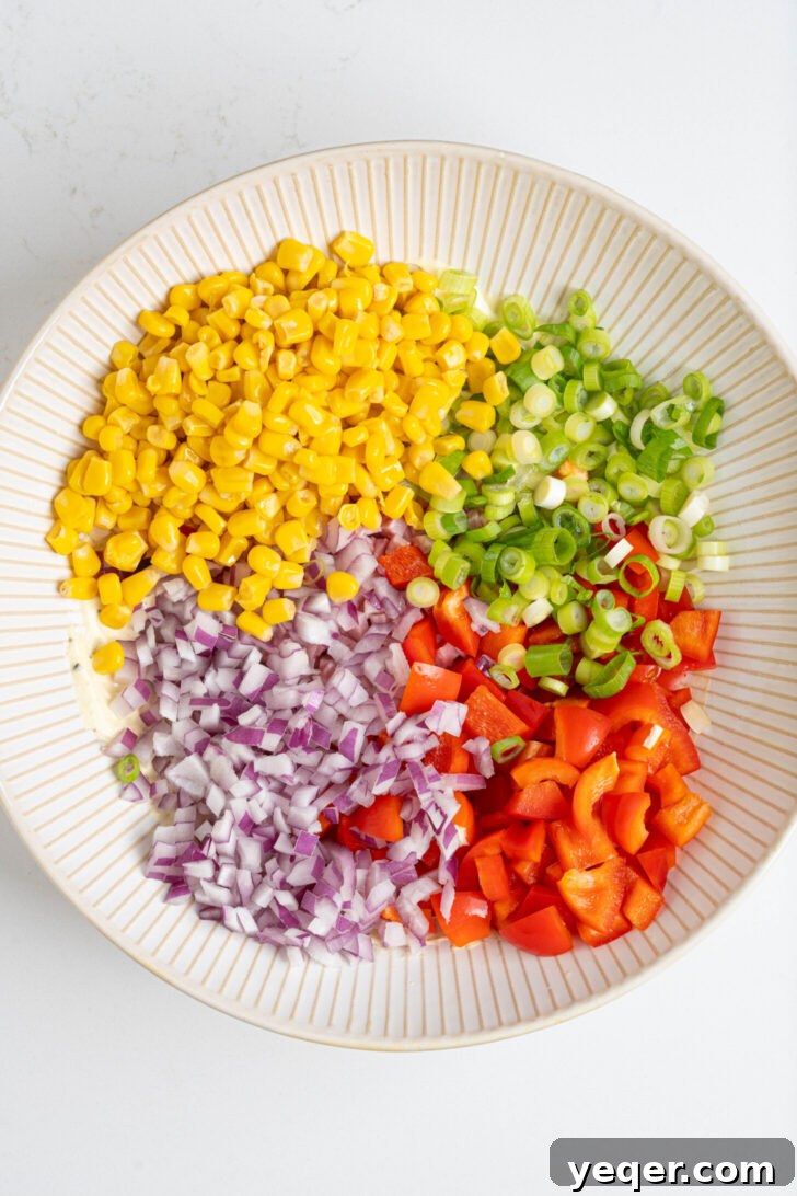Signature Puerto Rican Macaroni Salad 6 A colorful bowl with sweet corn, red and green onions, diced bell pepper, and ham, ready to be mixed into a salad.