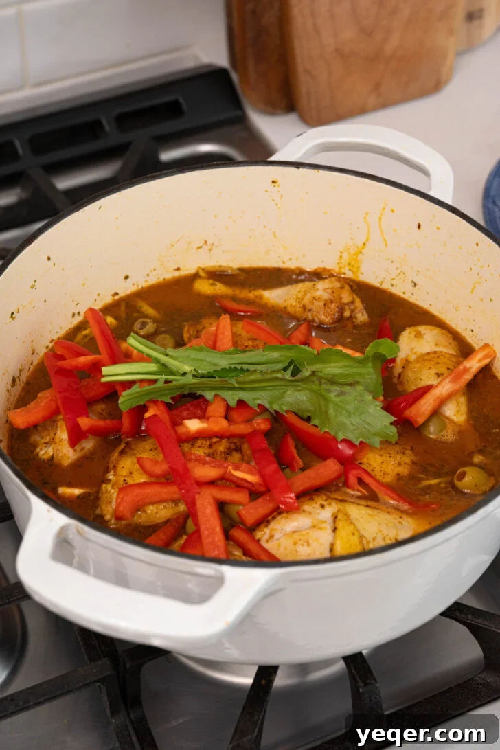 One-Pot Wonder Chicken Stew 7 Adding chicken, broth, olives, bell pepper, and culantro to the pot, ready for simmering.