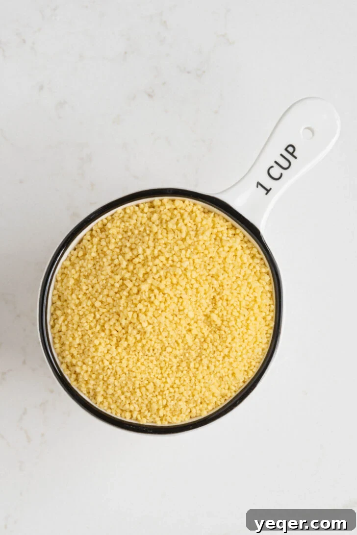 The Secret to Perfectly Fluffy Couscous 5 A measuring cup filled with dry couscous grains.