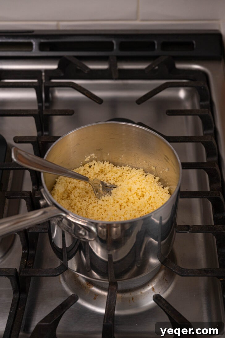 The Secret to Perfectly Fluffy Couscous 10 A pot of cooked couscous being fluffed with a fork.