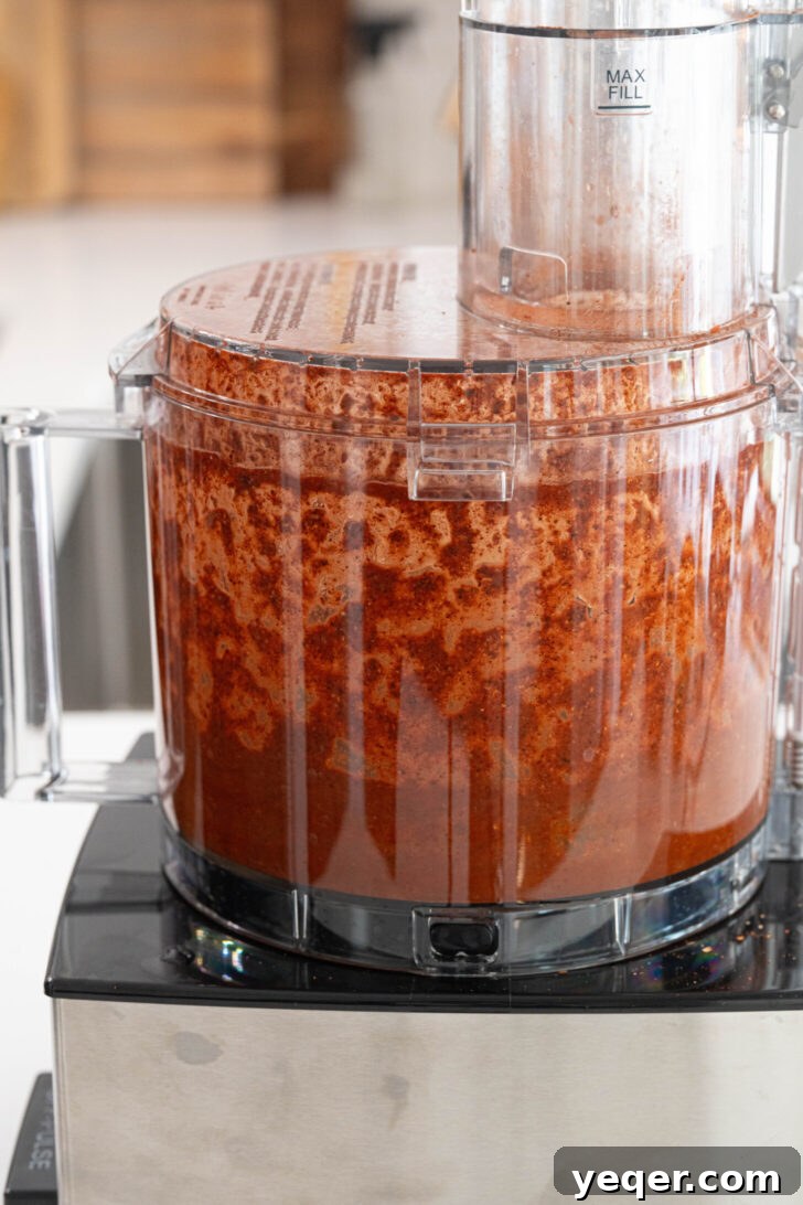 Homemade Achiote Paste in Minutes 6 A food processor bowl containing a smooth, reddish-orange achiote paste, perfectly blended and ready for use.