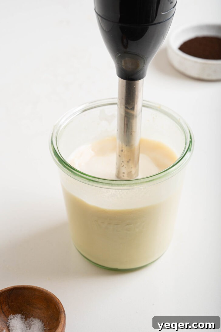 Salty Sweet Honeycomb Tahini Latte 5 Honey, milk, and tahini being frothed together in a glass with a handheld frother, creating a creamy, light mixture.