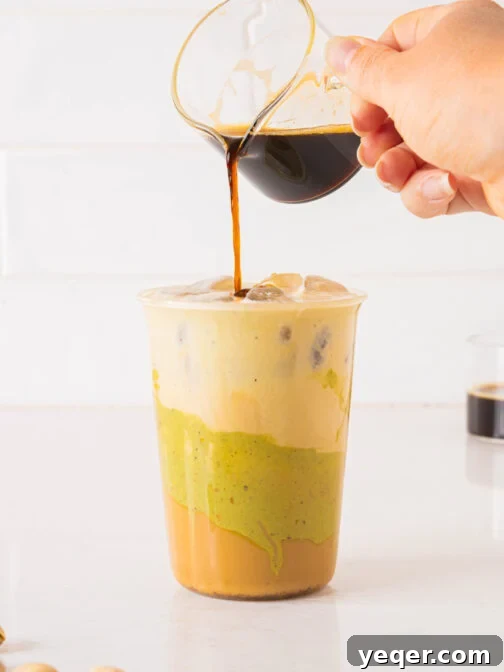 An espresso shot pouring over a pistachio latte.