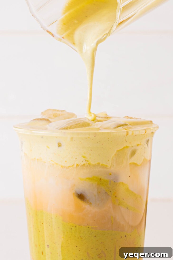 Signature Pistachio Dream Latte 7 Pistachio cold foam being poured over a latte in a glass with ice, showing the layered effect.