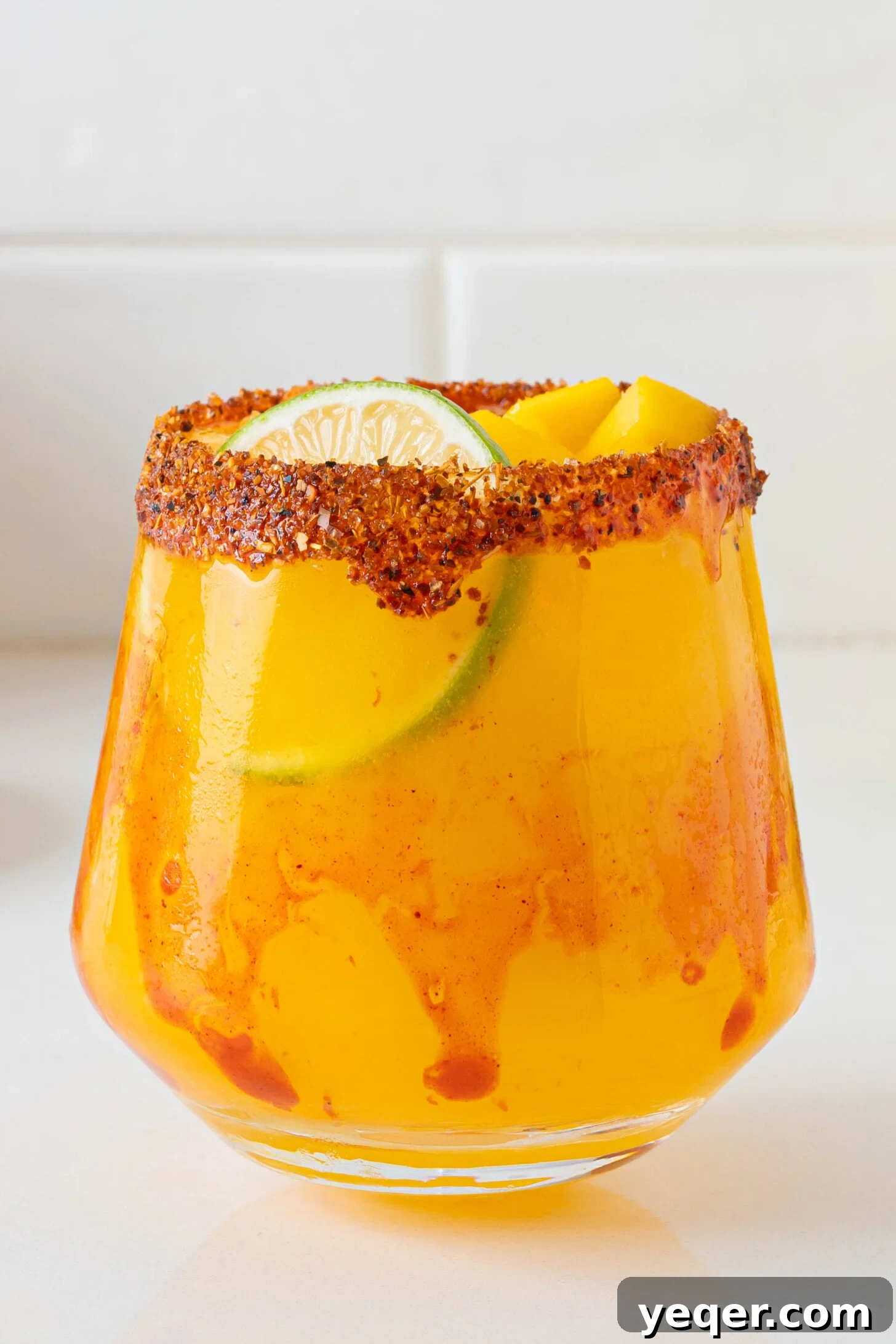 Golden Mango Margarita Bliss for All 9 A beautifully presented fresh mango margarita with a Tajin rim and a lime wheel garnish, resting on a wooden surface in warm lighting, ready to be enjoyed.