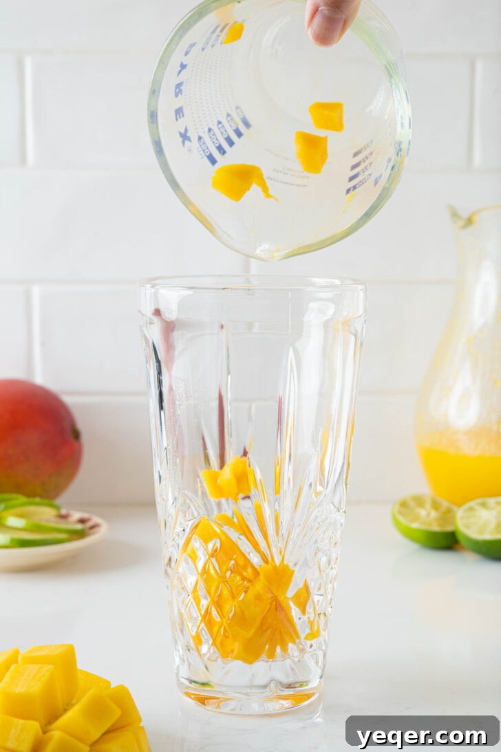 Golden Mango Margarita Bliss for All 5 Diced fresh mango chunks, lime juice, and agave nectar being muddled together at the bottom of a cocktail shaker.