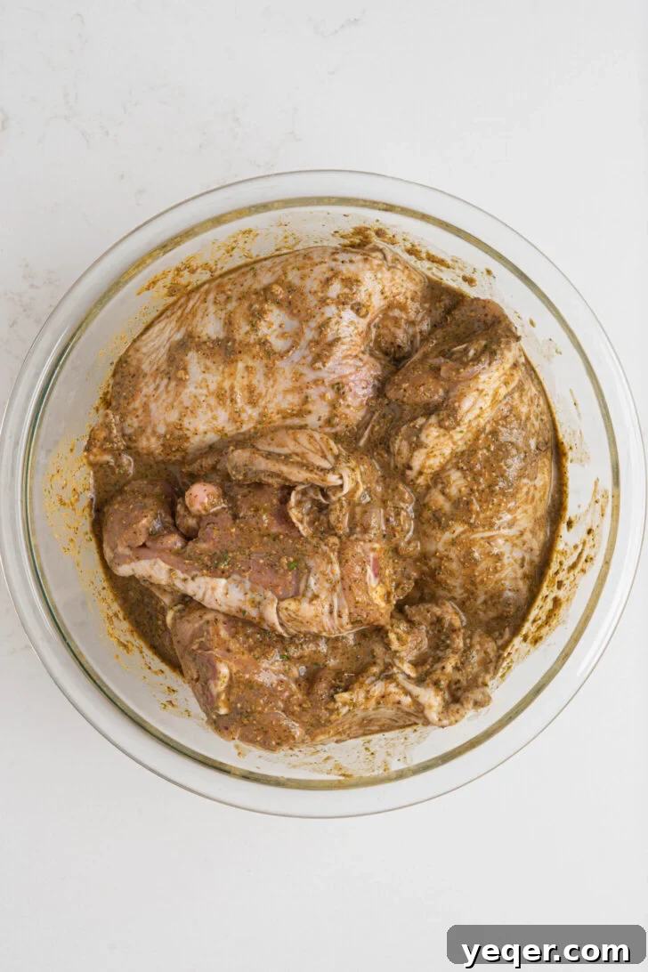 Flavorful Homemade Pollo Asado 5 Chicken pieces thoroughly coated in the rich, red Pollo Asado marinade, resting in a bowl before chilling.