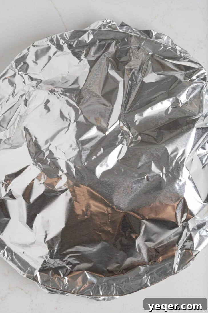 Flavorful Homemade Pollo Asado 7 A plate of freshly cooked Pollo Asado covered with aluminum foil, allowing the chicken to rest.