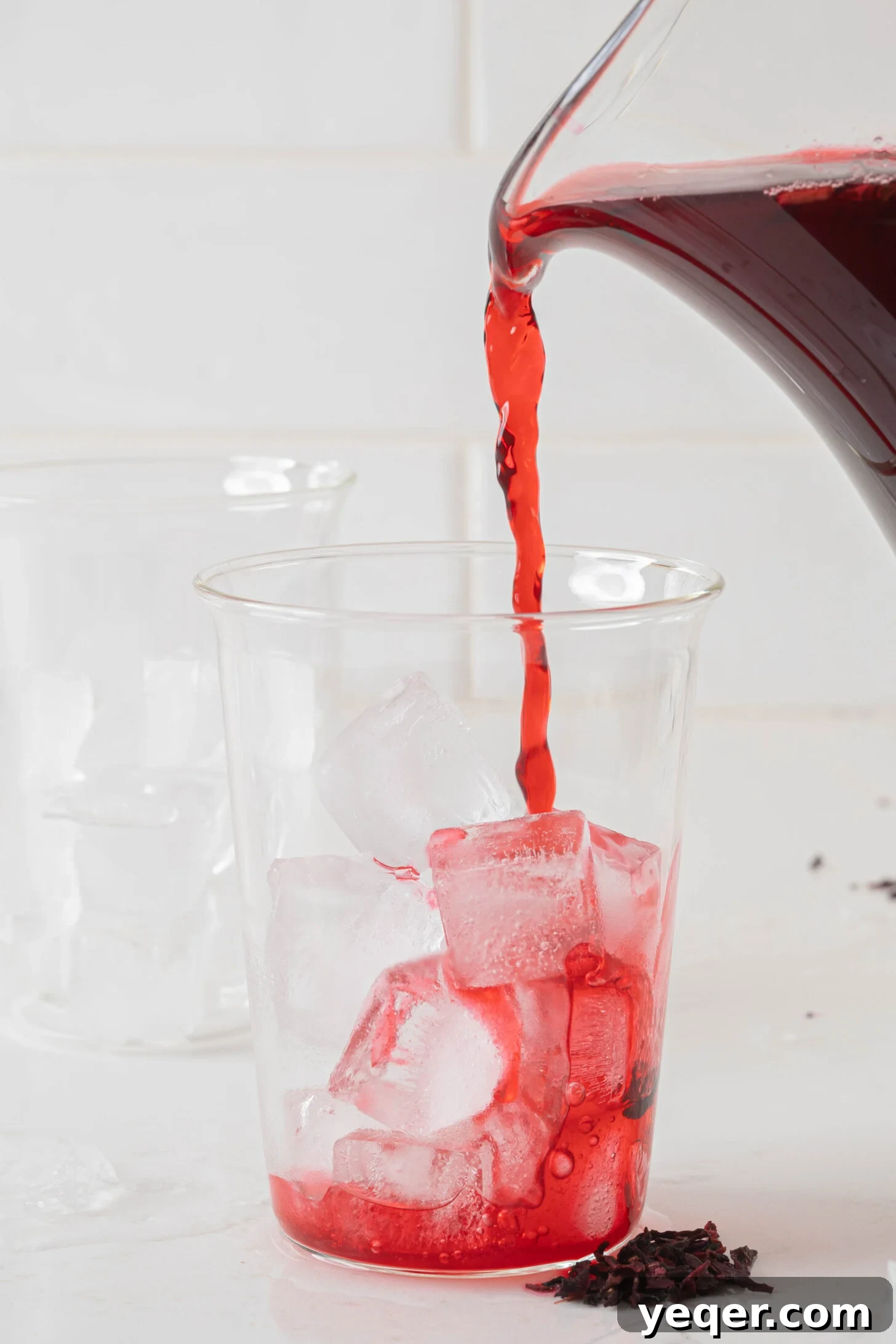 Agua de jamaica pouring into a glass.
