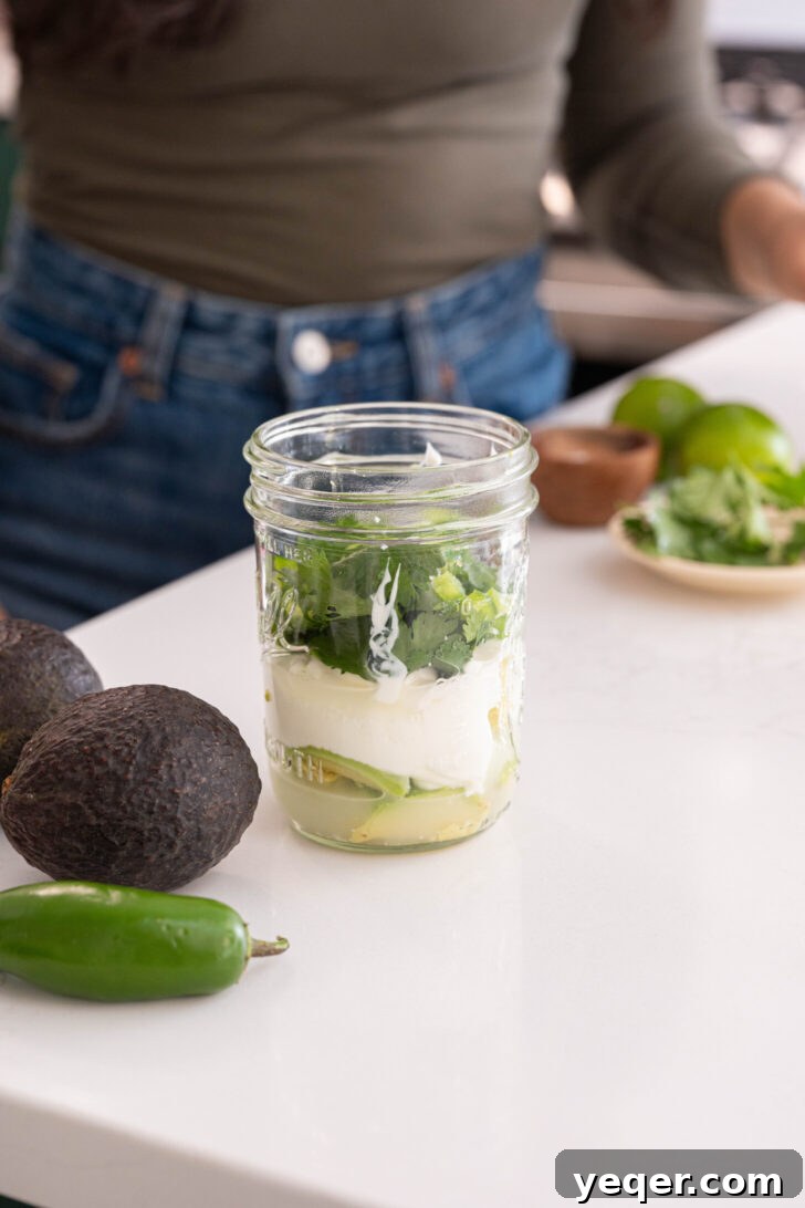 Velvety Greek Yogurt Avocado Dip 5 A wide-mouthed jar filled with avocado, Greek yogurt, lime juice, cilantro, and jalapeño, ready for blending.