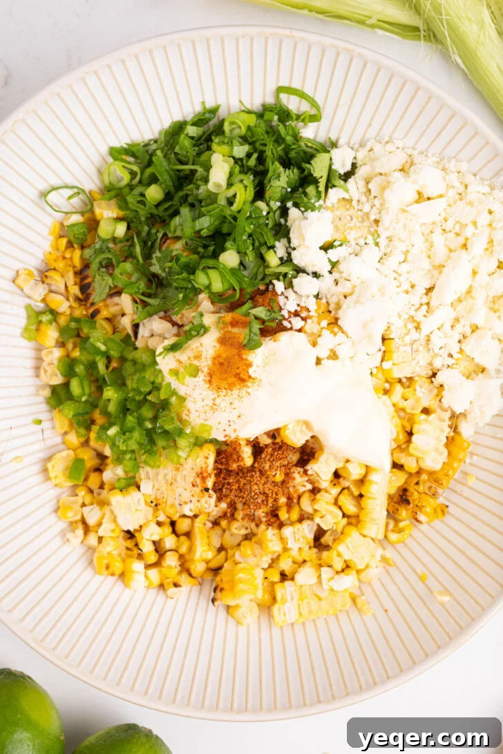 Grilled Mexican Street Corn Dip 7 Grilled corn kernels, herbs, cheese, and seasonings being added to a large mixing bowl.