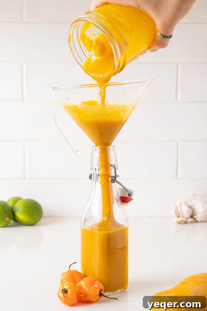 Tropical Fire Mango Habanero Sauce 8 Hot sauce pouring into a bottle.