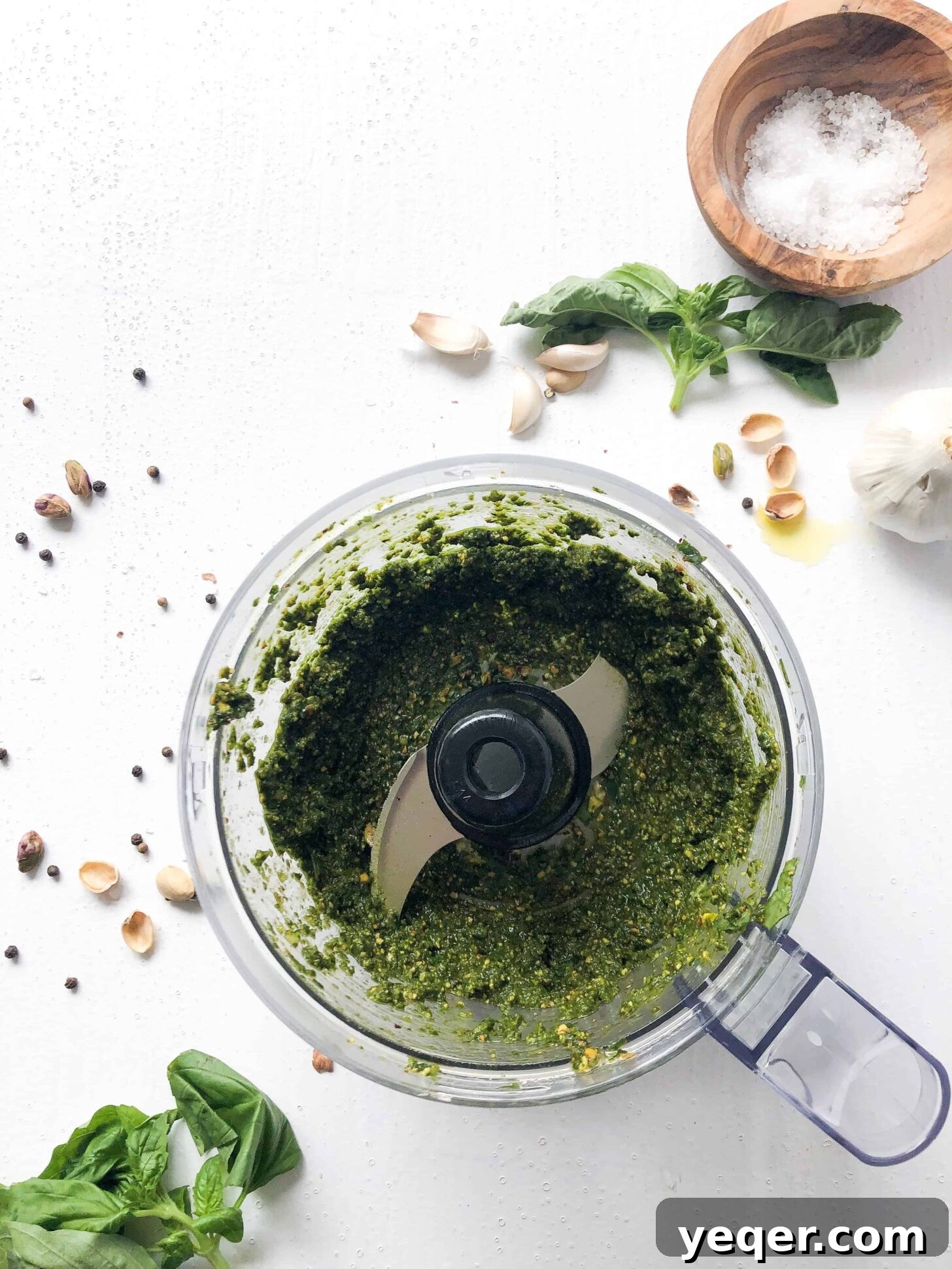 A food processor filled with freshly made, vibrant green vegan pistachio pesto, showing a chunky yet smooth consistency.