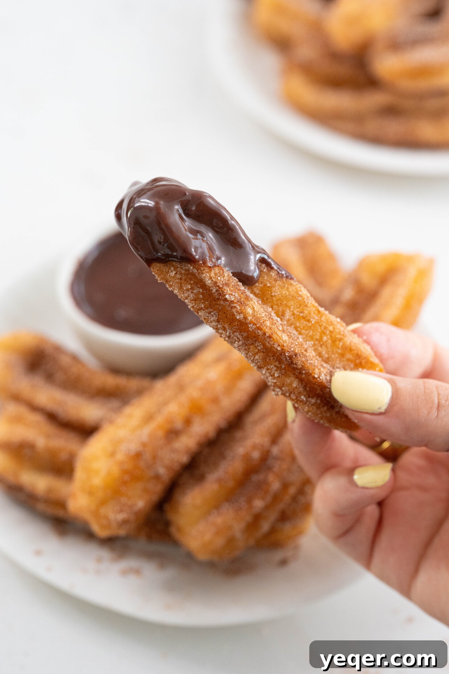 Homemade Golden Churros with Decadent Chocolate Sauce 12 A close-up shot of a churro being dipped into a swirl of velvety chocolate sauce.