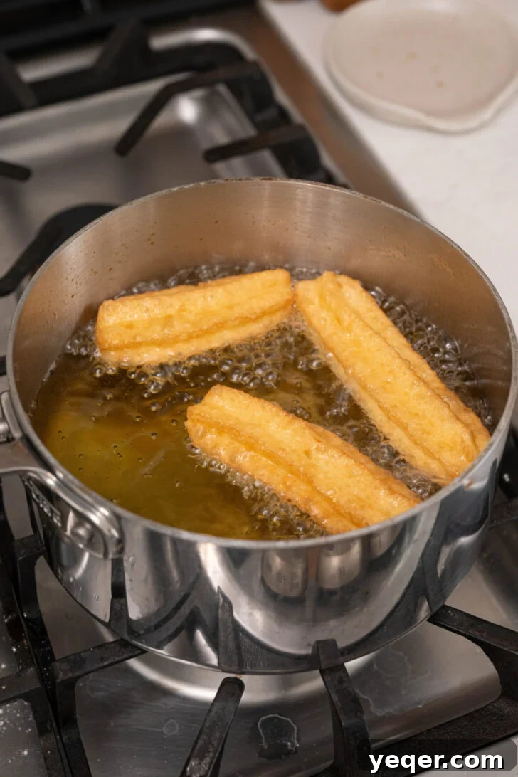 Homemade Golden Churros with Decadent Chocolate Sauce 8 Churro dough being piped into hot oil, frying to a golden crisp.