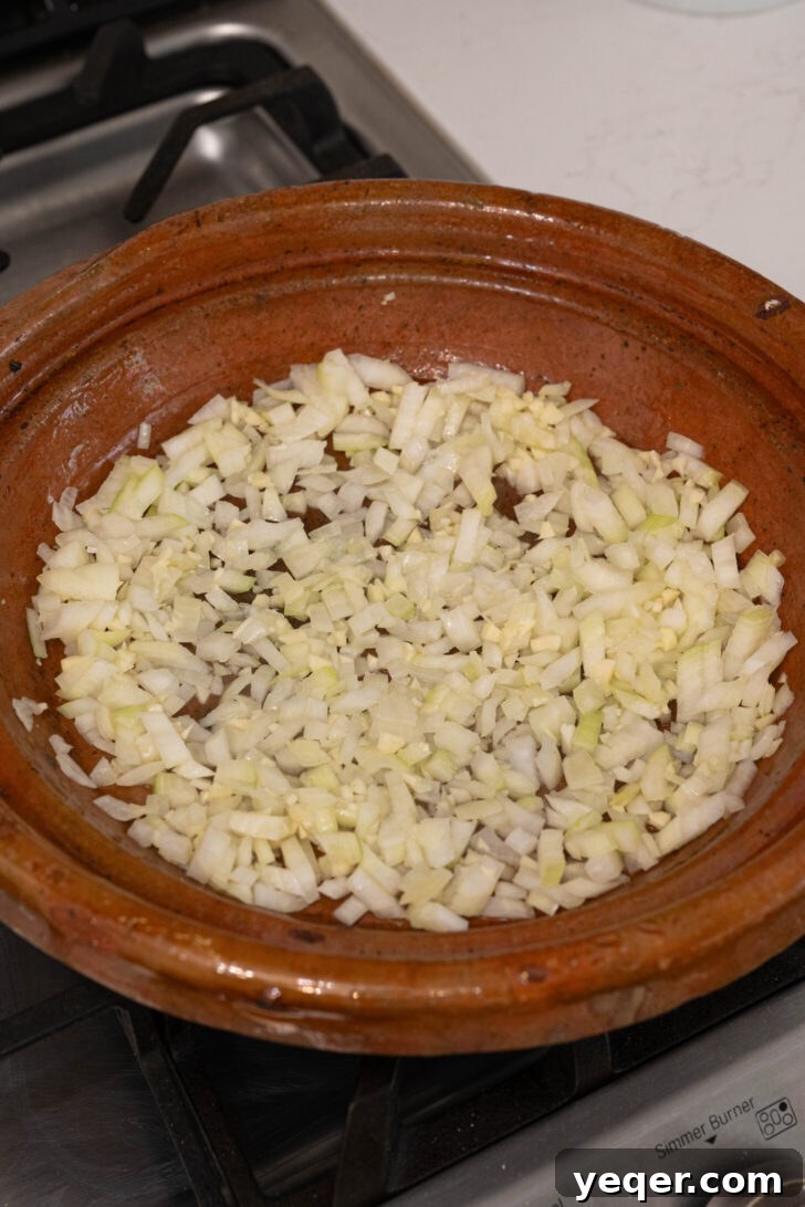 Moroccan Tagine with Okra and Tomatoes 4 A tagine pot with sliced onions and minced garlic simmering in olive oil.