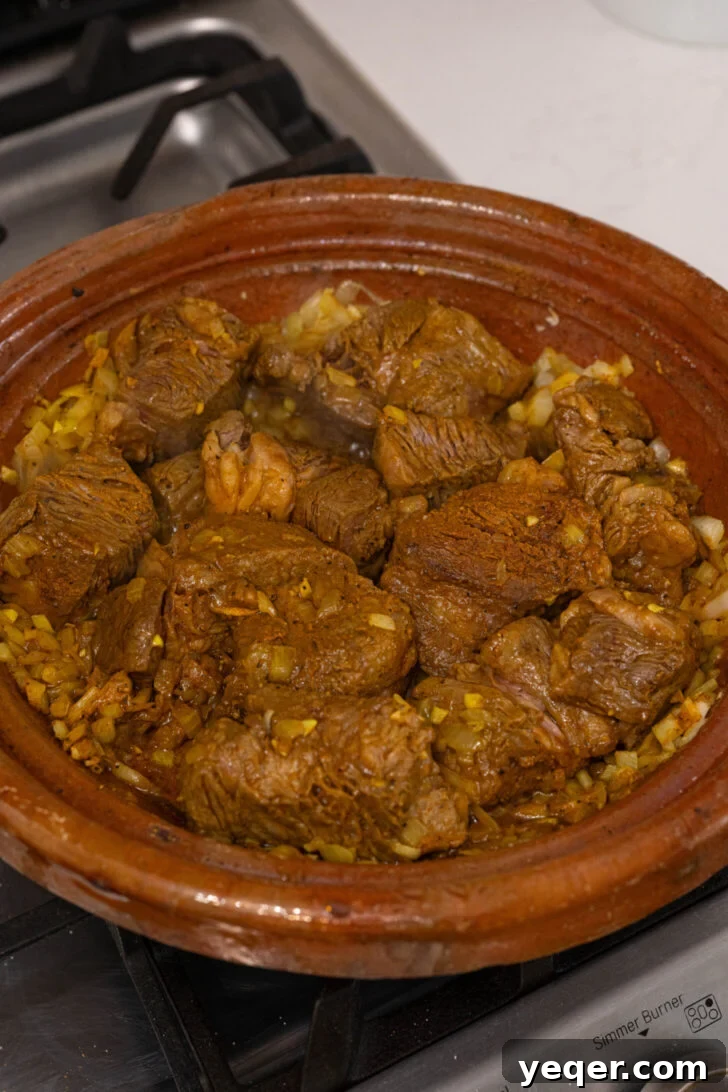 Moroccan Tagine with Okra and Tomatoes 5 Chunks of beef seasoned with spices browning in a tagine pot alongside softened onions.
