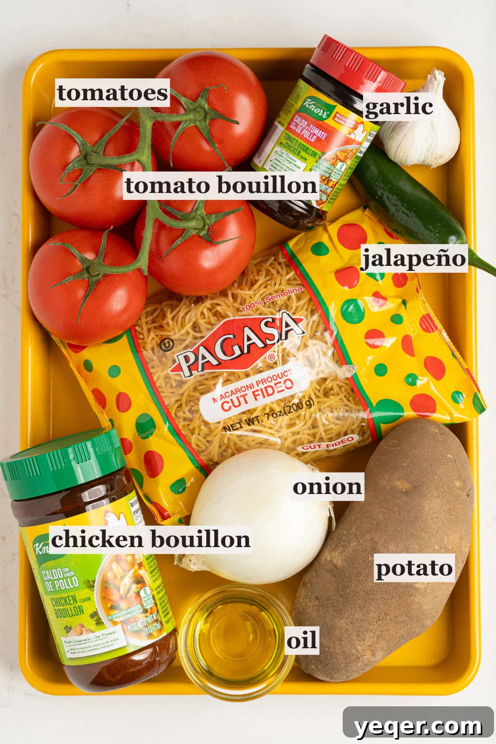 Vibrant Tomato Vermicelli Soup 4 A tabletop arrangement of fresh ingredients for Sopa de Fideo, including bright red roma tomatoes, a white onion, garlic cloves, a jalapeño pepper, and a package of fideo noodles.