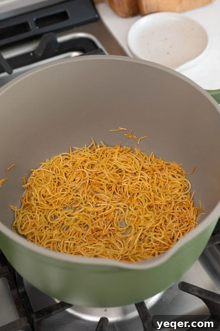 Vibrant Tomato Vermicelli Soup 6 Close-up view of fideo noodles being toasted in a pot with oil, showing their transformation to a golden brown color.